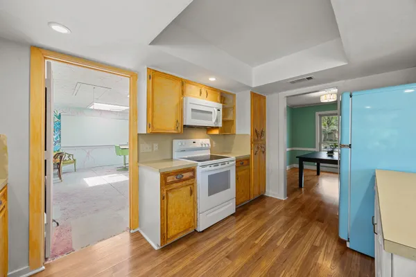 a kitchen with a stove a refrigerator and a view of living room