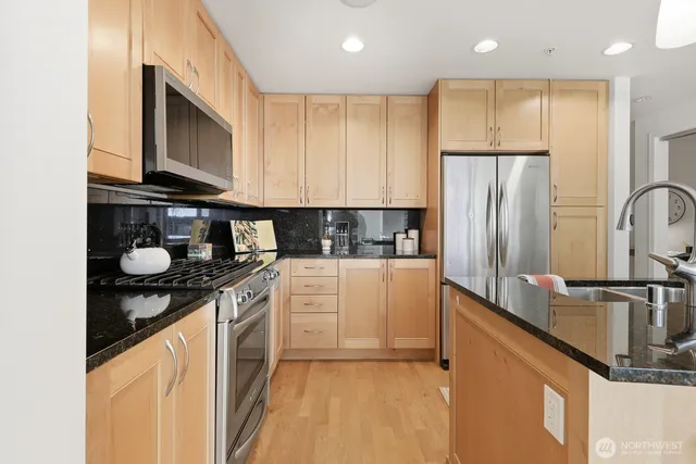 a kitchen with stainless steel appliances granite countertop a refrigerator stove top oven and sink