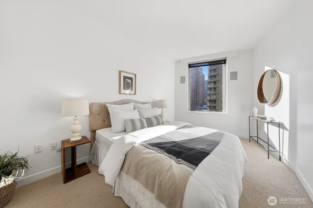 a bedroom with a bed a mirror and a potted plant on table