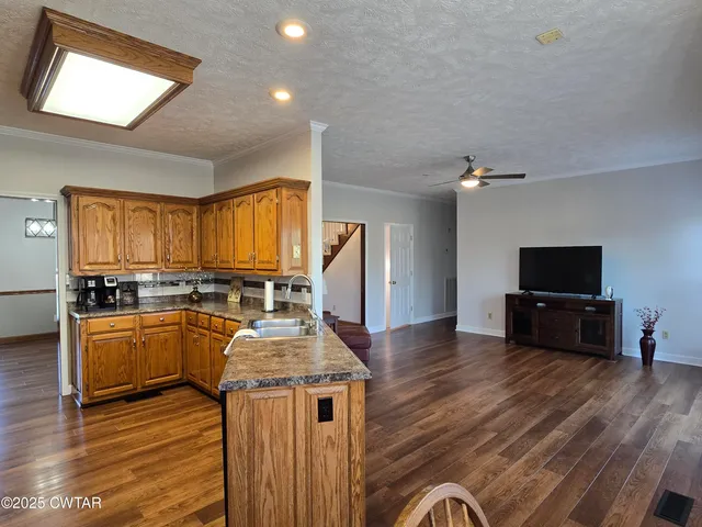 a living room with furniture a flat screen tv and kitchen view