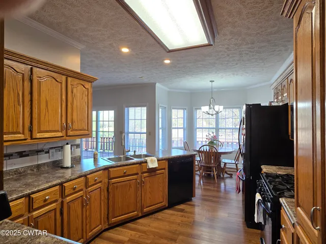 a kitchen with stainless steel appliances granite countertop a refrigerator a sink dishwasher a stove and a dining table with wooden floor