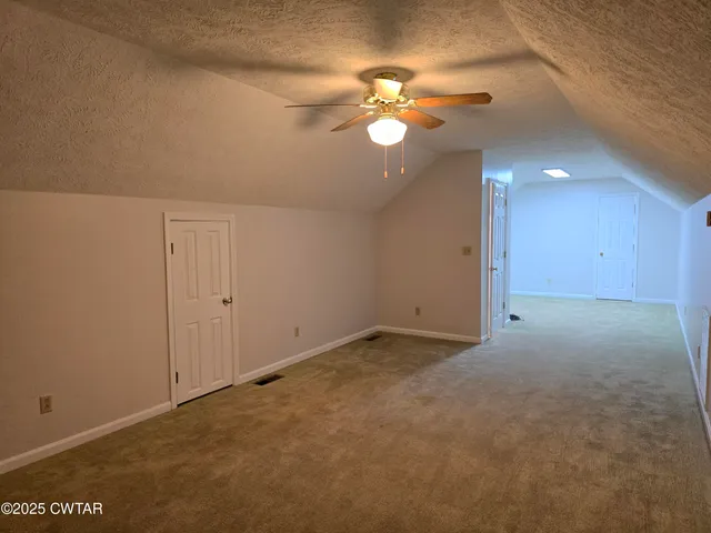 a view of an empty room with a chandelier fan