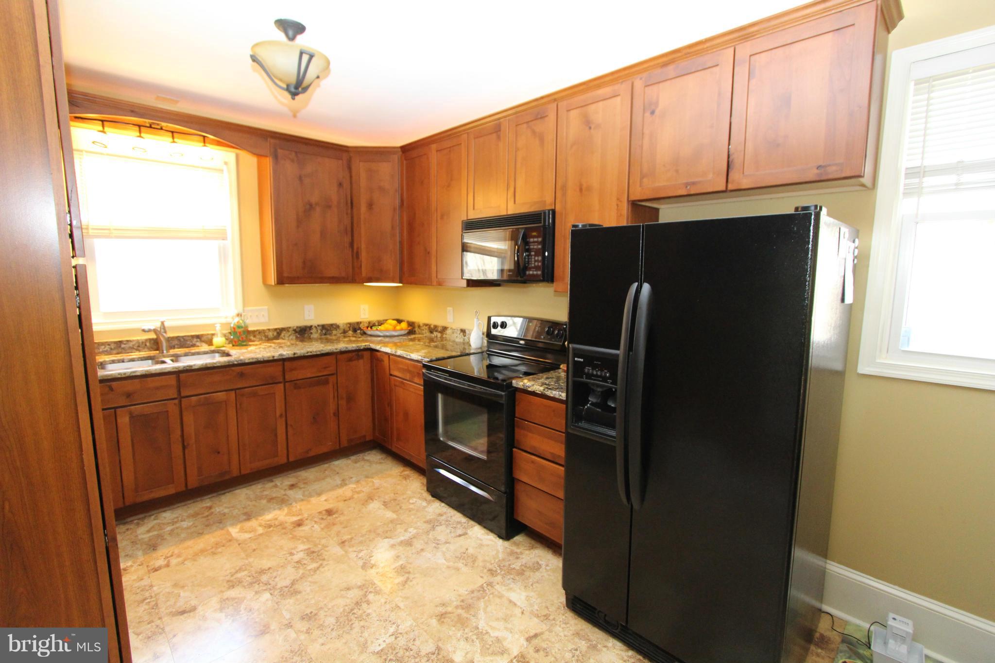8720 Windsor Mill Road Baltimore, MD 21244 - Photo 6 of 27 a kitchen with granite countertop a refrigerator and a stove top oven