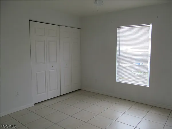 a view of an empty room with window and closet area