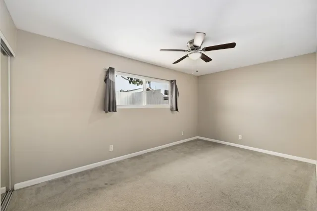 an empty room with windows and fan