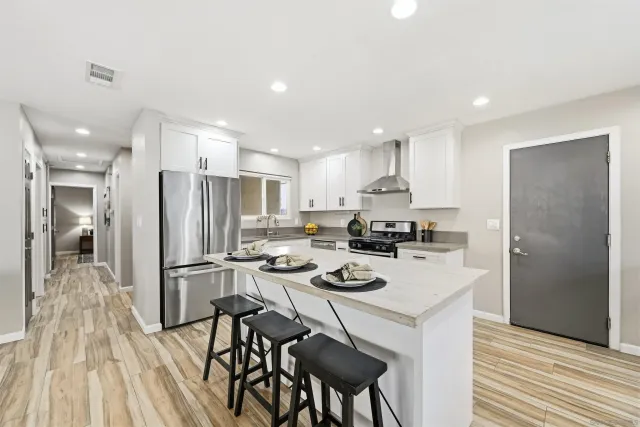 a kitchen with a refrigerator a stove and a dining table with wooden floor