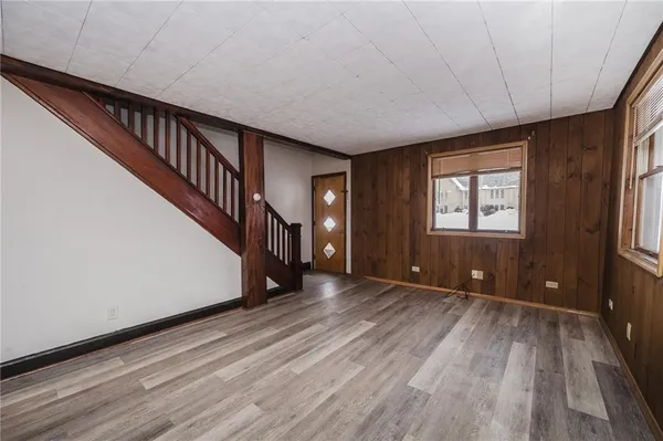 a view of an empty room with wooden floor and stairs