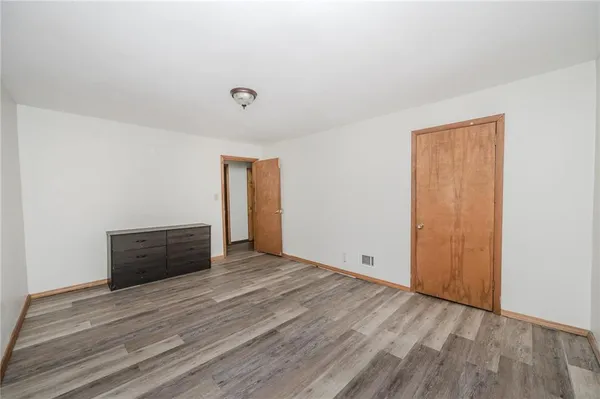 an empty room with wooden floor and cabinet
