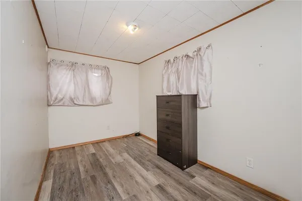 an empty room with wooden floor closet and windows