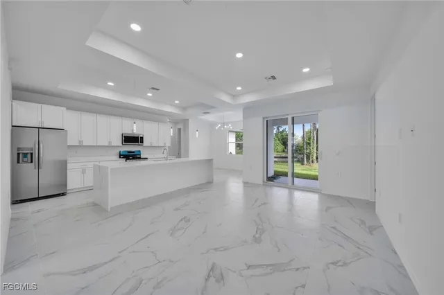a large white kitchen with kitchen island a stove a sink and cabinets
