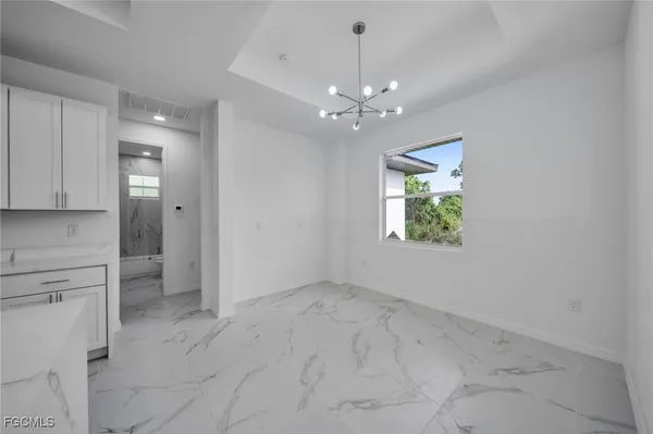 an empty room with chandelier fan and windows