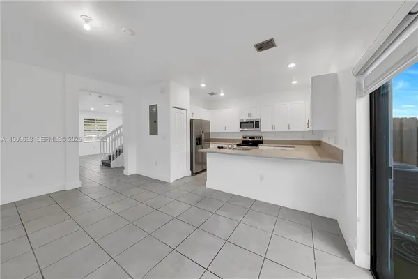 a kitchen with stainless steel appliances kitchen island granite countertop a refrigerator and a stove top oven