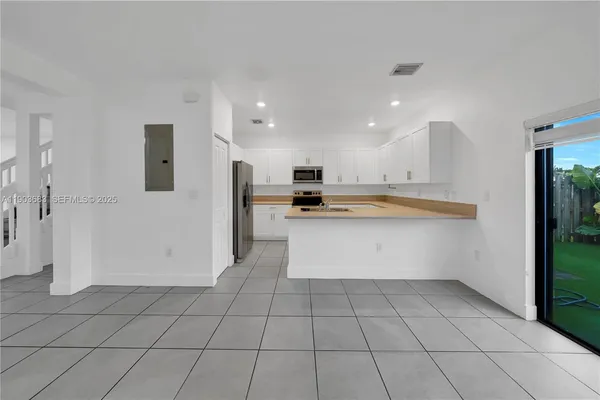 a view of kitchen with granite countertop cabinets and refrigerator