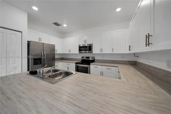 a kitchen with granite countertop a refrigerator stove and sink