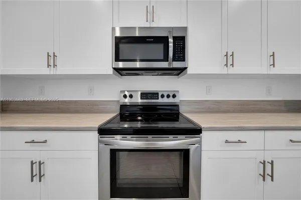 a kitchen with stainless steel appliances granite countertop white cabinets stove top oven and sink