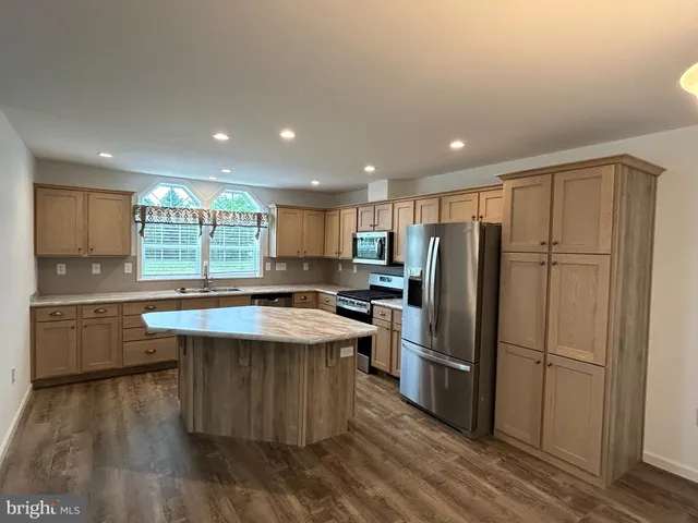 a kitchen with kitchen island a sink a stove a refrigerator and white cabinets