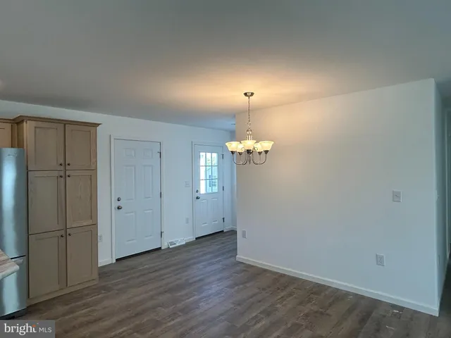an empty room with wooden floor chandelier fan and windows