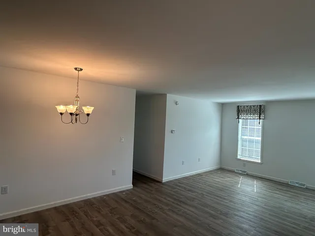 an empty room with wooden floor windows and cabinet