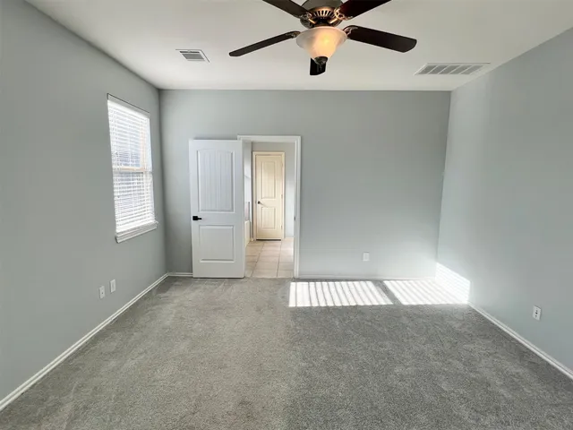 an empty room with a ceiling fan and windows