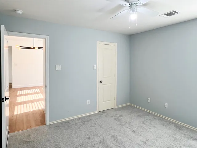 an empty room with a ceiling fan and window