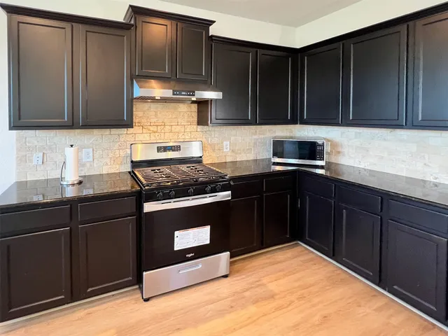 a kitchen with granite countertop wood cabinets stainless steel appliances and a sink