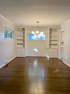 an empty room with wooden floor chandelier and entryway