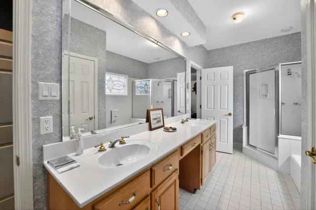 a bathroom with a sink double vanity granite tub shower and a mirror