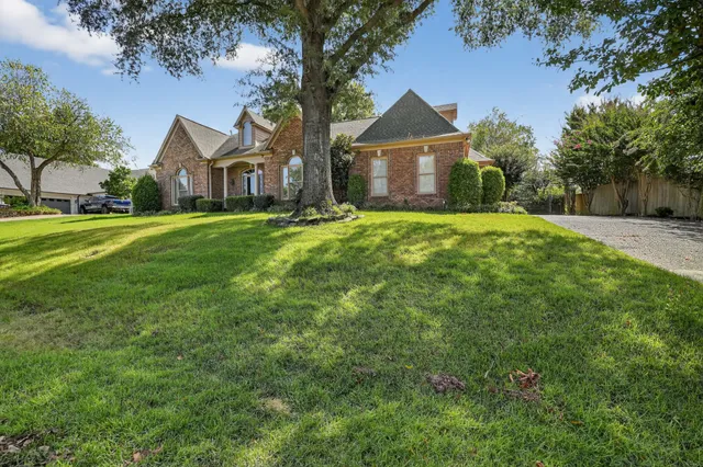a front view of a house with a yard and trees