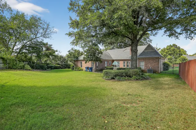 a view of a house next to a big yard and large trees