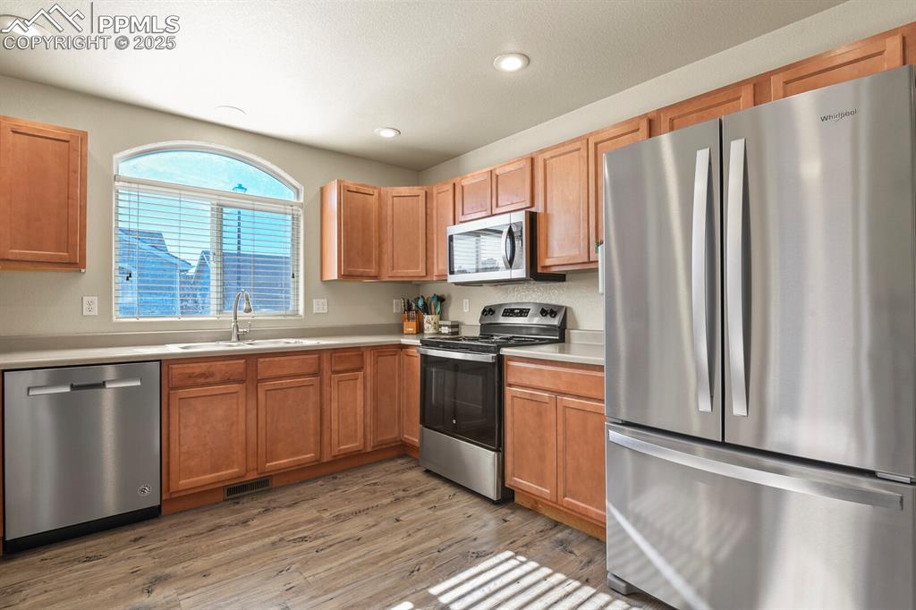 7394 Owings Point Peyton, CO 80831 - Photo 6 of 21 a kitchen with stainless steel appliances granite countertop a refrigerator a sink dishwasher a stove and white countertops with wooden floor