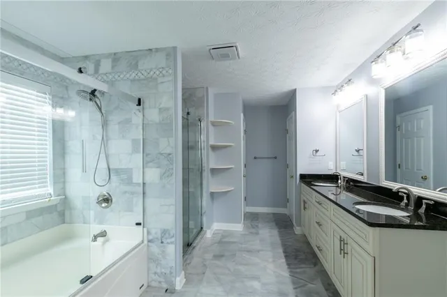 a bathroom with a granite countertop sink mirror bathtub and shower