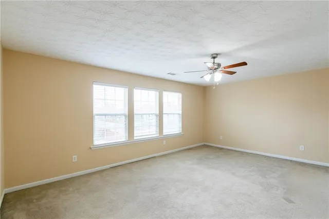 an empty room with windows and chandelier fan