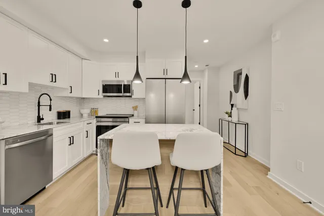 a kitchen with stainless steel appliances a table chairs refrigerator and microwave