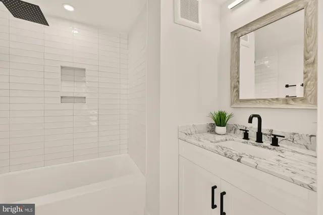 a bathroom with a granite countertop sink a mirror and a bathtub