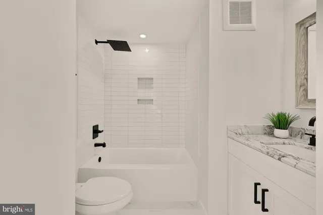a bathroom with a granite countertop sink a toilet and shower