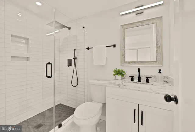 a bathroom with a granite countertop sink a toilet and shower