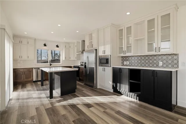 a kitchen with kitchen island granite countertop a refrigerator oven a sink and cabinets