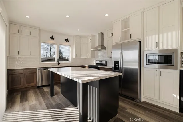 a kitchen with stainless steel appliances granite countertop a sink a stove a refrigerator and white cabinets