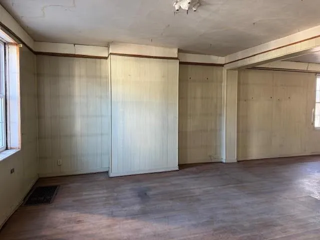 a view of an empty room with wooden floor and a window