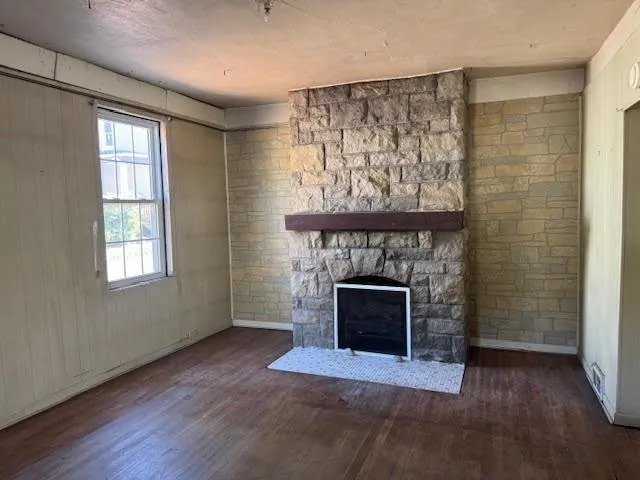 a view of an empty room with wooden floor fireplace and a window