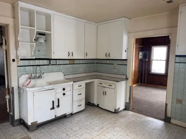 a kitchen with white cabinets and sink
