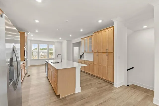 a kitchen with stainless steel appliances granite countertop a refrigerator a sink and a stove with wooden floor