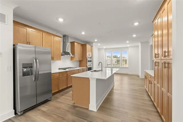 a large kitchen with stainless steel appliances granite countertop a refrigerator a sink dishwasher a stove and white countertops with wooden floor