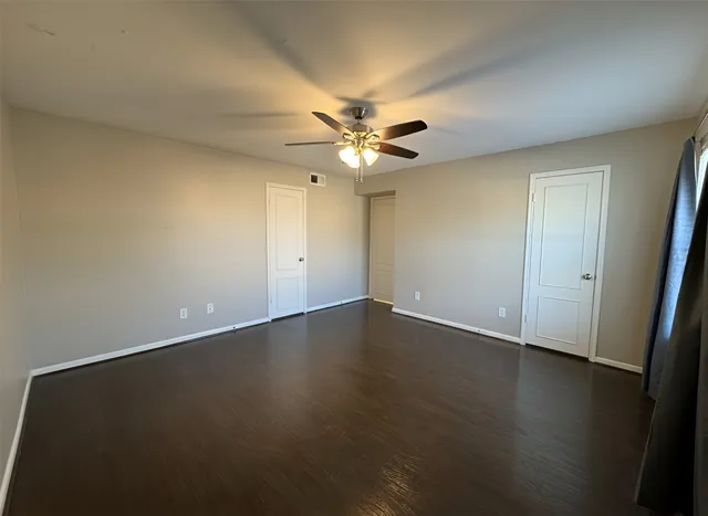 an empty room with wooden floor and fan