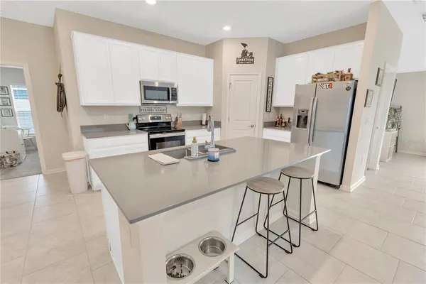a kitchen with stainless steel appliances a stove a sink a microwave a refrigerator a counter top space and cabinets