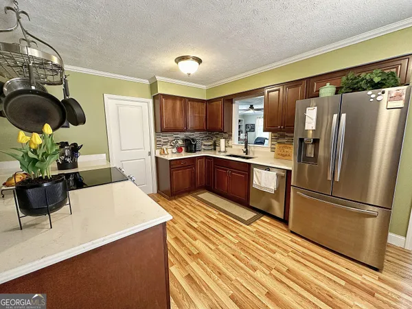 a kitchen with stainless steel appliances granite countertop a refrigerator a stove a sink a microwave and with wooden floor