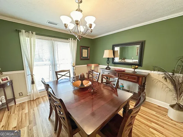 a view of a dining room with furniture a chandelier and wooden floor