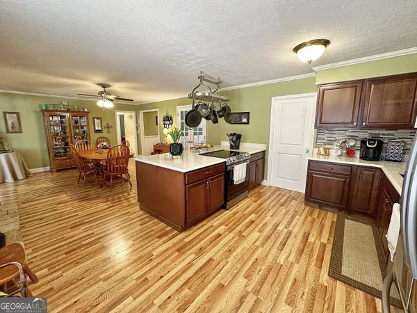 a large kitchen with stainless steel appliances a stove a sink dishwasher and a dining table with wooden floor
