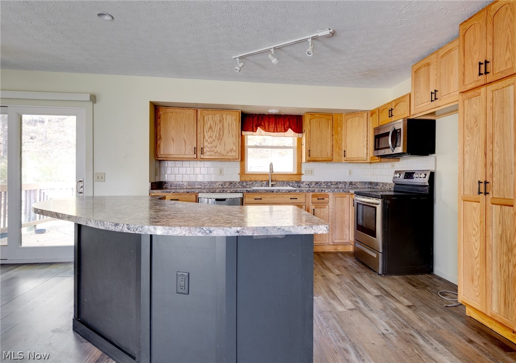 9416 Kieffer Road Mantua, OH 44255 - Photo 13 of 29 Kitchen with stainless steel appliances, decorative backsplash, light wood-type flooring, light countertops, and a textured ceiling