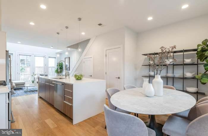 628 I Street Northeast, Unit 3 Washington, DC 20002 - Photo 3 of 32 a kitchen with stainless steel appliances kitchen island granite countertop a table chairs and a refrigerator